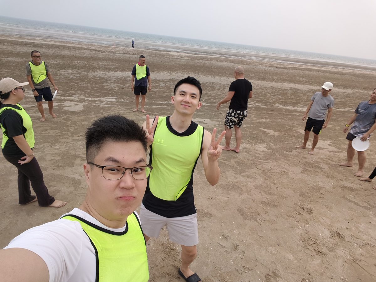 Two participants in team bibs grinning on the beach